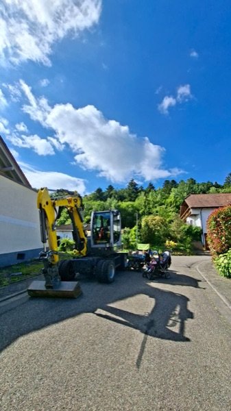 Ein gelber Bagger auf der Dorfstraße