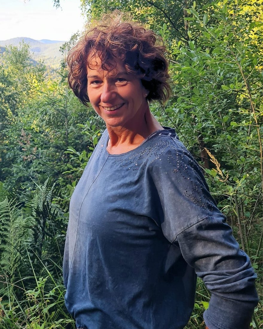 Doreen Steller lacht, im Hintergrund Wald und Hügel.